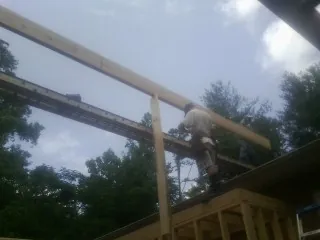 Carpenter setting a ridge beam over a new addition frame — Ice Dam Removal by Roofing Brothers in Leigh