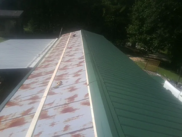 Old rusted panels beside newly installed green metal roofing — Wind Damage Roof Repair by Roofing Brothers in Leigh