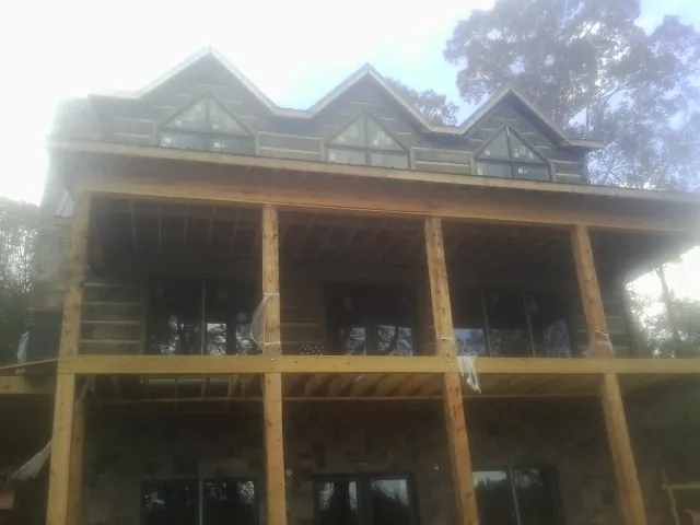 Dormers and porch framing on a large log home under construction — Roof Coating work by our crew in Leigh