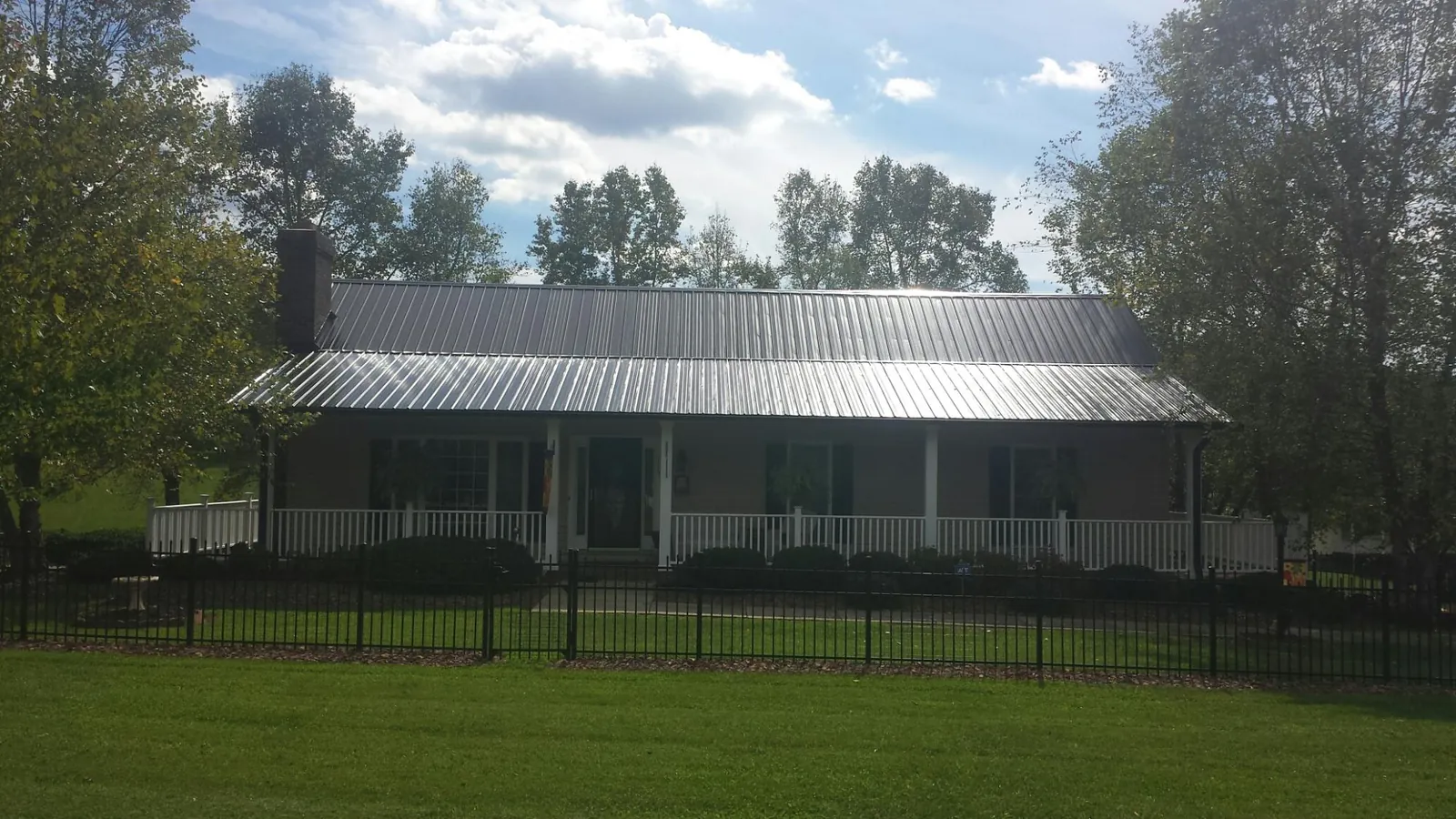 Gray metal roof on a brick ranch with a full width front porch — Gutter Guard Installation work by our crew in Leigh